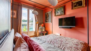 Ein Schlafzimmer mit einem Bett, einem Fernseher und einem Fenster mit Vorhängen.