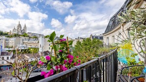 A balcony with a view of a cityscape, including a prominent cathedral and residential buildings. - Montmartre View - Appt avec vue sur le Sacré-Cœur (Paris)