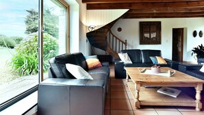 Ein Wohnzimmer mit Holzboden, einer Treppe, einem schwarzen Ledersofa und einem Couchtisch aus Holz.