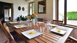Ein Esstisch mit Tellern, Besteck und Gläsern, dazu ein Blumenstrauß mit gelben Blumen.
