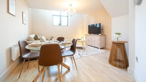 Un coin repas comprenant une table ronde, des chaises, un téléviseur et une petite table d’appoint sur laquelle est posé un vase.