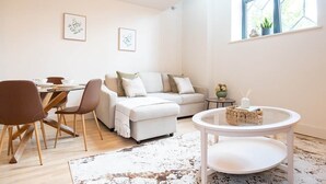 Un salon moderne comprenant un canapé, des fauteuils, une table à manger et une petite table basse ronde.