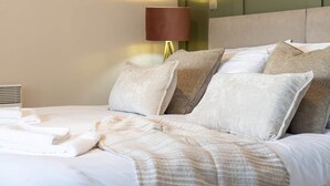 Un lit bien fait, recouvert d’une couverture à motifs, une lampe de chevet et un radiateur fixé au mur.