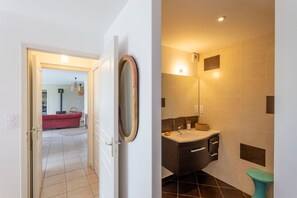 A bathroom with a sink, mirror, and tiled walls. - La Ville Barbier - Belle maison avec piscine (Médréac)