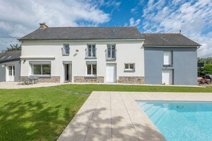 Une maison à deux étages avec une piscine, une pelouse et un espace patio.