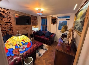 A cozy living room with a fireplace, a television mounted on a stone wall, a comfortable sofa, and a decorative lamp.