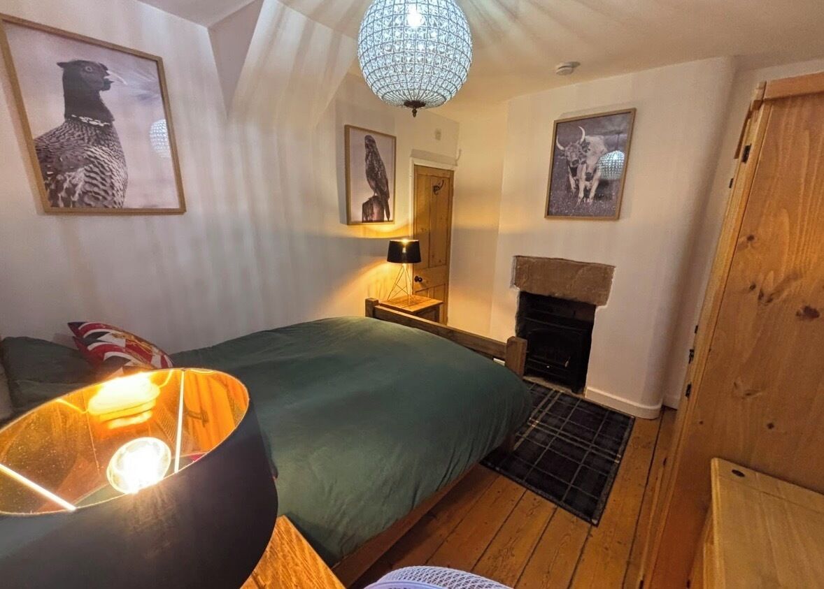 A room with a bed, a fireplace, and framed pictures on the walls.