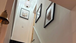 A staircase with a black and white checkered carpet, white walls, and framed pictures on the wall. - Cliff View Cottage Holiday Let (Matlock Bath)