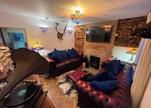 A cozy living room with a fireplace, a leather sofa, and a mounted deer head.