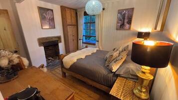 A cozy bedroom with a bed, a fireplace, a dining table, and a chandelier.