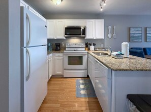 A modern kitchen with white cabinetry, a built-in microwave, a stove, and a sink. - New Listing - Fresh Calendar | Perdido Dunes | On the Beach + Outdoor Pool + Near Florabama (Orange Beach)