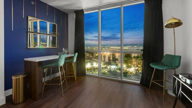 Ein modernes Zimmer mit einem großen Fenster, einer Bar und Blick auf eine Stadtlandschaft.