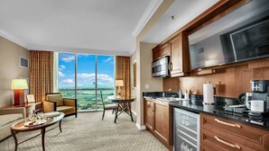 Una camera d'albergo con angolo cottura, zona pranzo vista panoramica e salotto con tavolo e sedie.