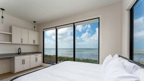 Ein Schlafzimmer mit einem großen Bett, Meerblick und einer Küchenzeile.