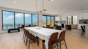 Eine moderne Küche mit Meerblick, ein Essbereich mit Tisch und Stühlen sowie ein großes Fenster zum Meer.