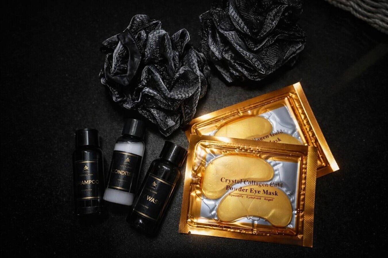 A skincare set including a powder eye mask, two bottles of shampoo, and a black cloth.