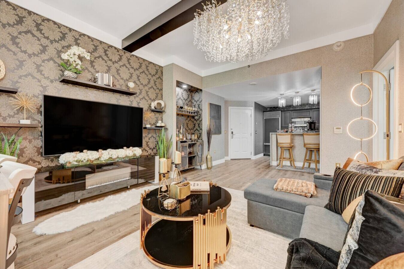 A modern living room with a large TV, a round coffee table, and a grey sofa.
