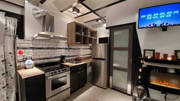 Una cocina moderna con un refrigerador de acero inoxidable, un horno empotrado y una estufa a gas.