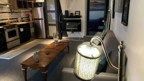 Una sala de estar moderna con un sofá, una mesa de centro de madera, una lámpara decorativa y una mesita con un jarrón.