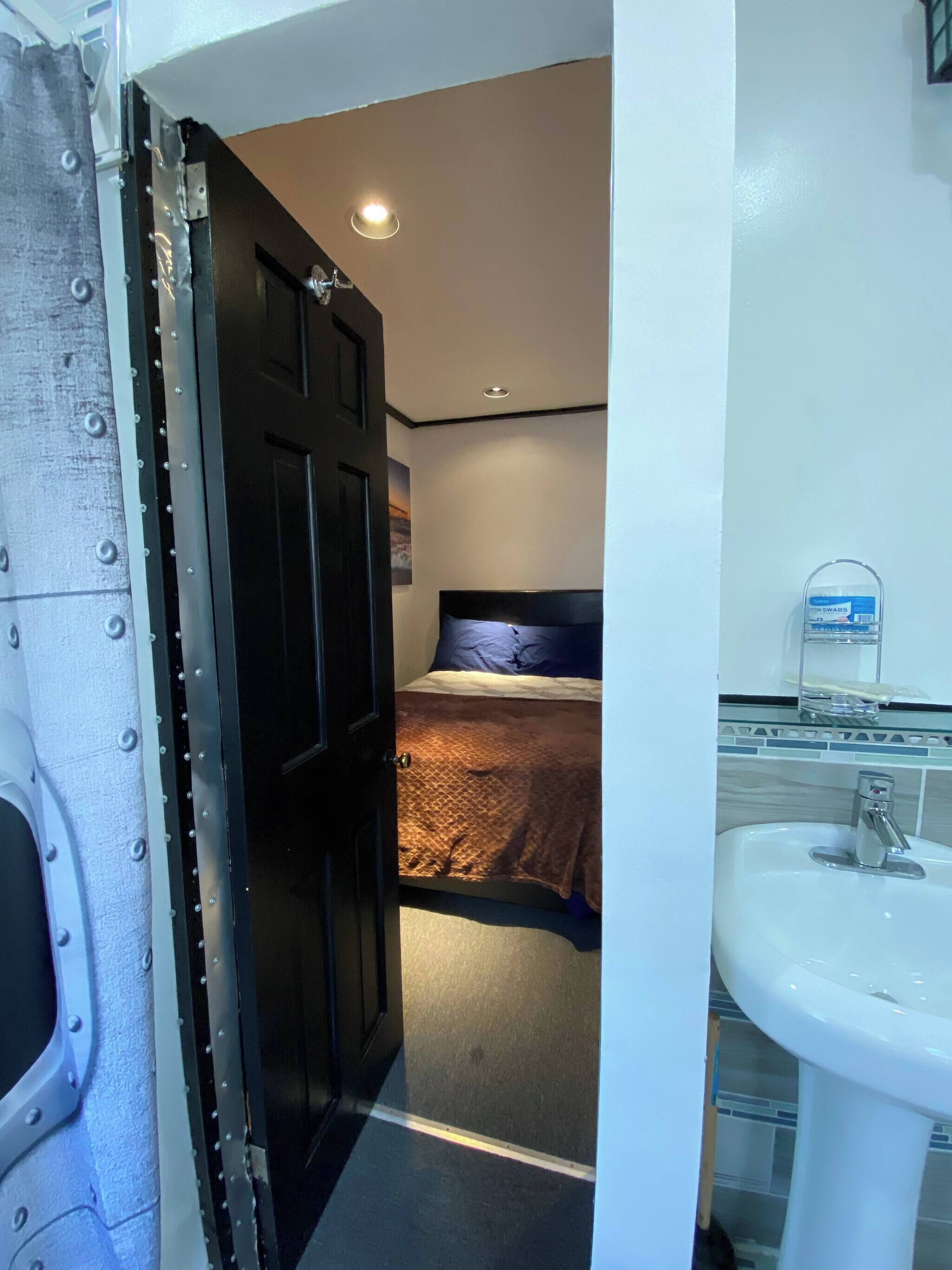 Ein Hotelzimmer mit einem Bett, einem Badezimmer mit Waschbecken und einer Tür zu einem weiteren Zimmer.