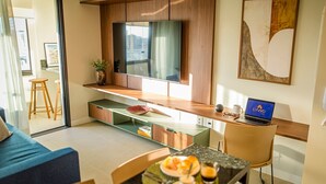 A modern living room with a TV, a laptop, and a dining area with a glass table and chairs. - Parking Space, View, and Complete Amenities in the City Center | LYVVO (Campinas)
