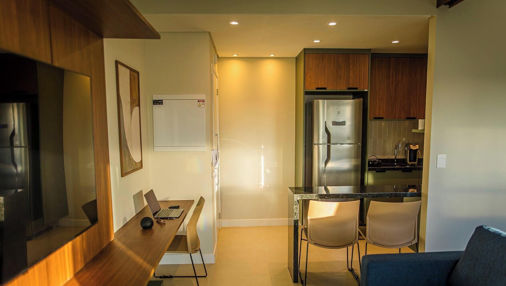 A compact kitchen with a refrigerator, microwave, and stove. There is a dining area with a table and chairs.