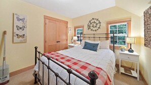 A bedroom with a bed, a nightstand, a window, a door, and wall decorations.
