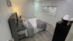 Une chambre à coucher avec un lit, une table de chevet, une fenêtre et un petit objet décoratif accroché au mur.