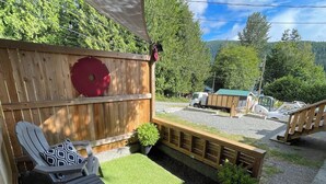 Une terrasse avec deux chaises longues, une petite table et une plateforme en bois.