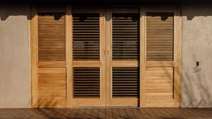 Une porte à deux battants en bois, avec des traverses horizontales, un plancher en bois et un mur muni d’une petite prise électrique.