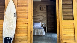 Un bâtiment en bois avec une planche de surf appuyée contre une porte en bois.