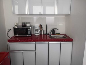 Eine kleine Küche mit Mikrowelle, Kaffeemaschine und Spüle.