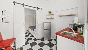 Cocina compacta con refrigerador, pileta y mostrador de recepción.