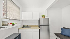 Una cucina compatta con frigorifero, forno a microonde e macchina del caffè.