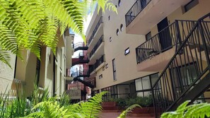 A multi-story building with balconies, a staircase, and surrounding greenery. - Design Apartment Facing Plaza Belén & Church - Historic La Candelaria & Rooftop (Bogotá)