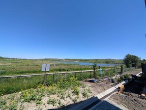 A view of a river, a fenced garden with yellow flowers, and a distant body of water. - 2 Bedroom Suite (Contact for Short-stay) (Calgary)