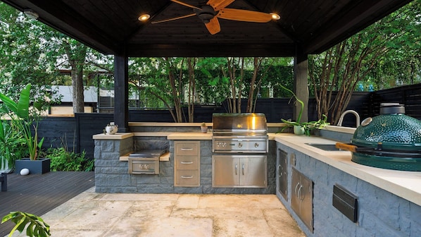 An outdoor kitchen with a grill, a built-in oven, and a ceiling fan.