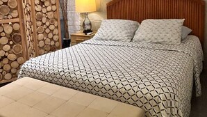 Una camera da letto con un letto, un comodino, una lampada e un quadro appeso al muro.