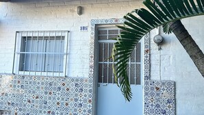 Un edificio con facciata in tegole, una porta con un numero e una finestra con inferriate.