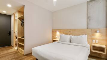 Un dormitorio moderno con cabecera de madera, una cama grande, mesitas de noche con lámparas y un armario empotrado.