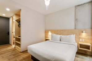 Un dormitorio moderno con cabecera de madera, una cama grande, mesitas de noche con lámparas y un armario empotrado.