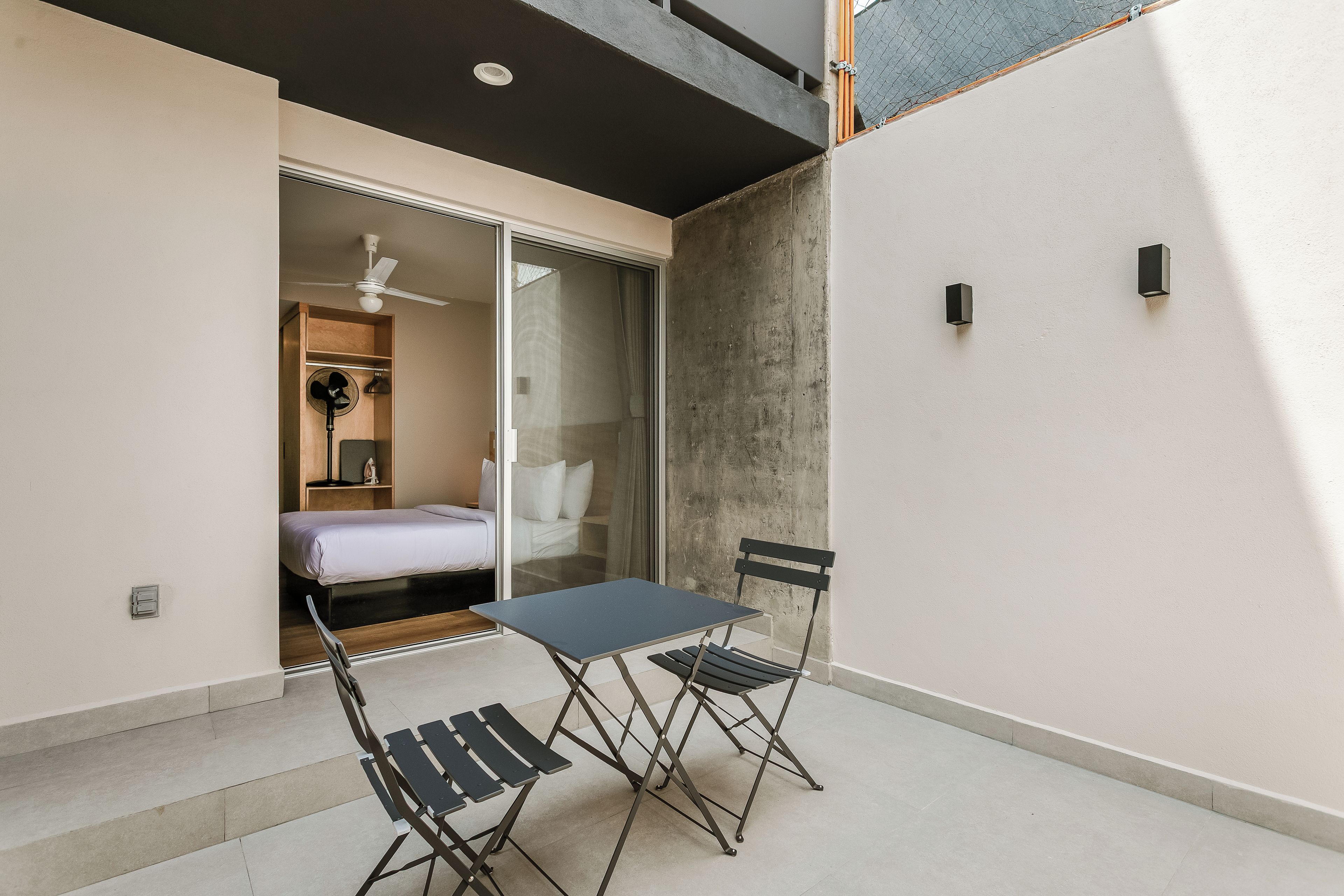 Un balcón con una mesa, sillas, una cama y un ventilador de techo.