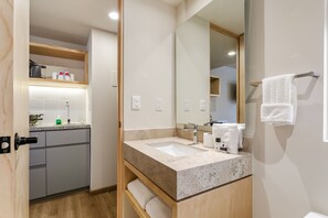 Un baño moderno con un lavamanos grande, espejo y barra para toallas.