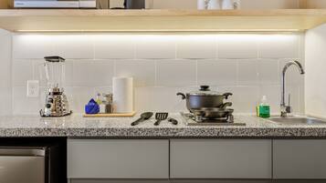 A kitchen with a granite countertop, a sink, a stove, and various kitchen utensils.