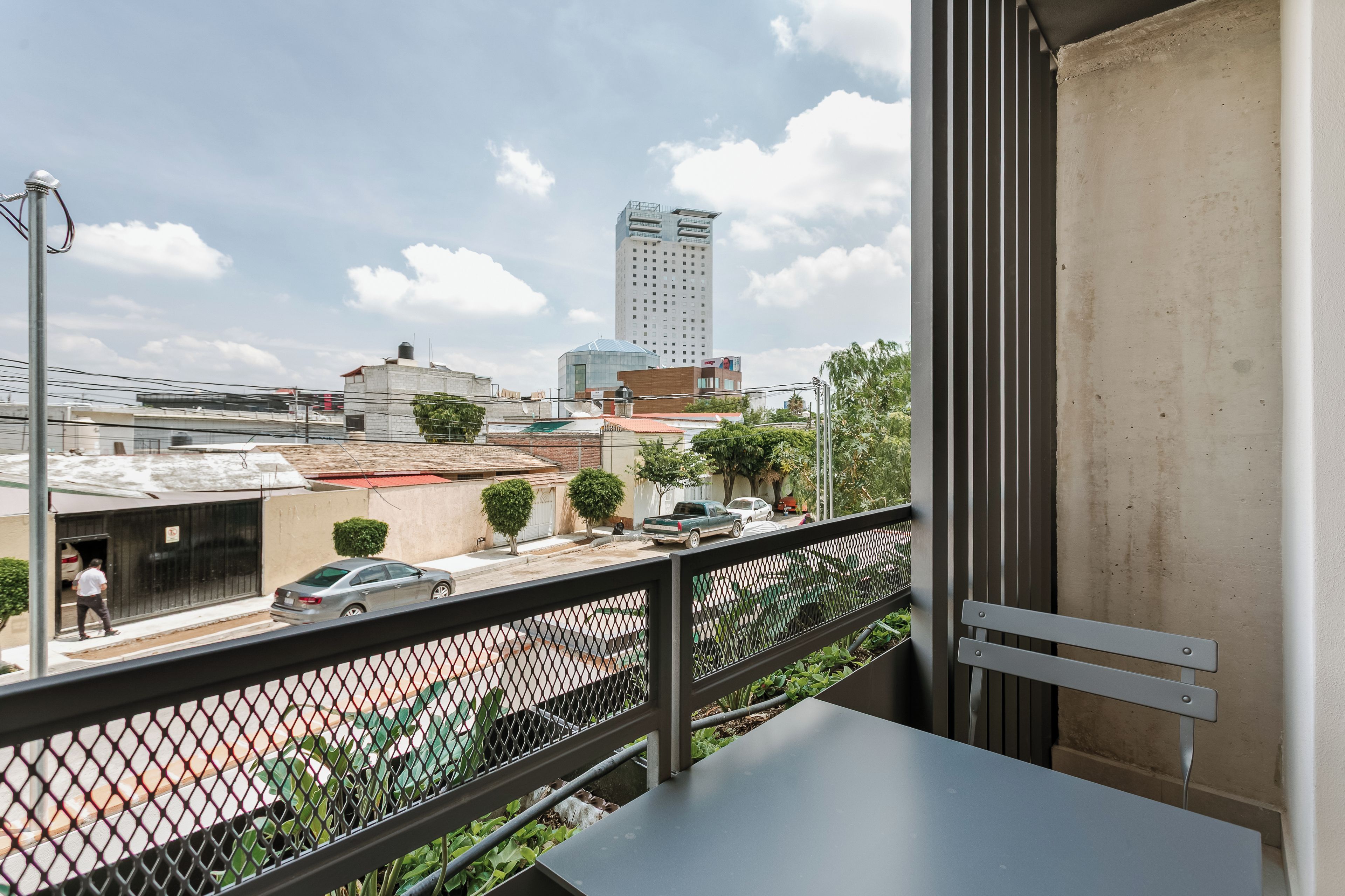 Un balcón con vista a un paisaje urbano, que incluye edificios y una calle.