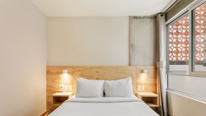 A hotel room with a bed, wooden headboard, bedside tables with lamps, and a window with a geometric pattern. - El Pocito By Homirent  (San José de los Olvera)