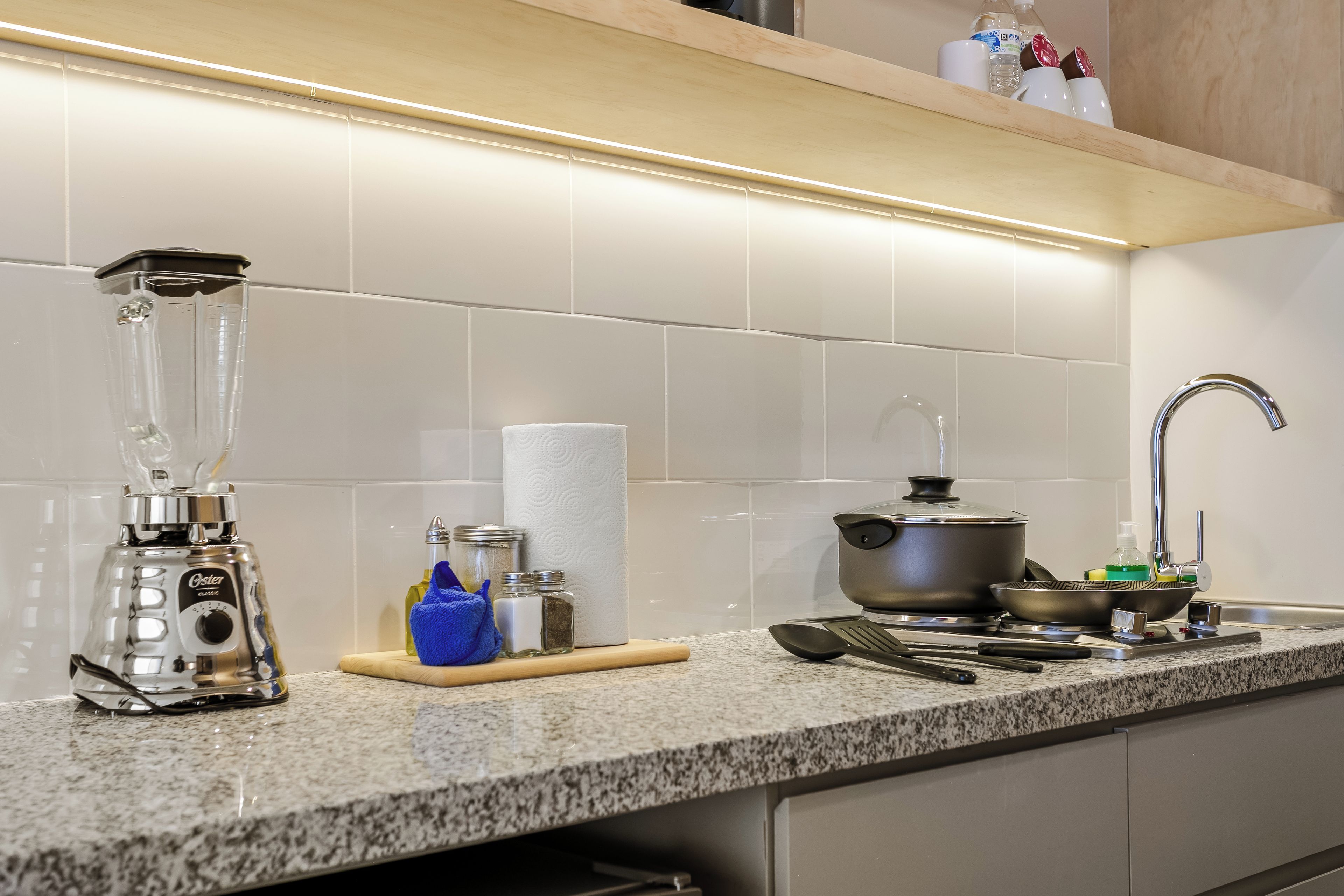 Una cocina con una licuadora, una tetera, una olla y varios utensilios en la encimera.