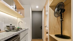 A narrow kitchen with a built-in oven, a sink, and a microwave. There is a wooden shelf above the counter and a fan on the right. - El Pocito By Homirent  (San José de los Olvera)