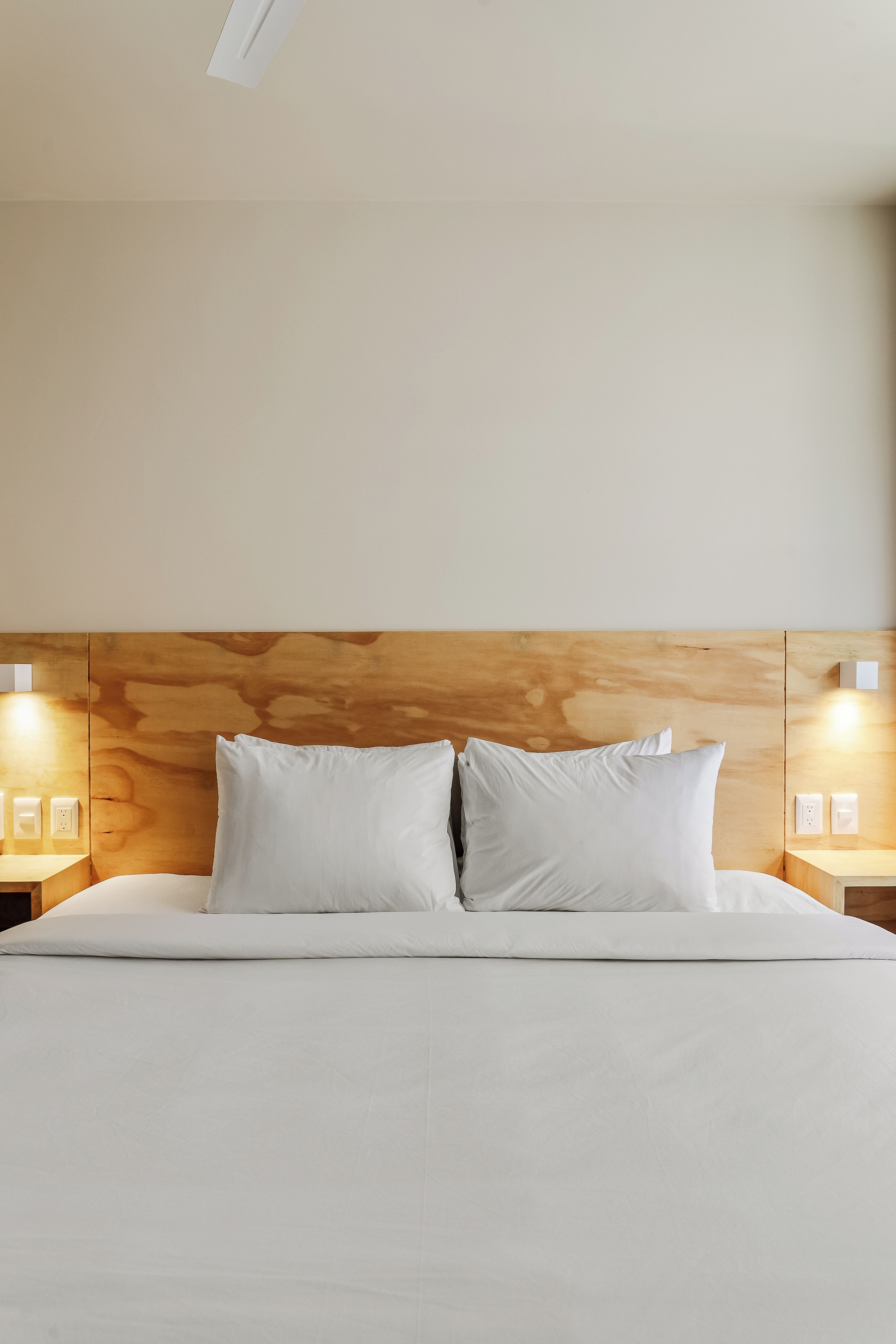 A hotel room with a large bed, wooden headboard, and bedside lamps.