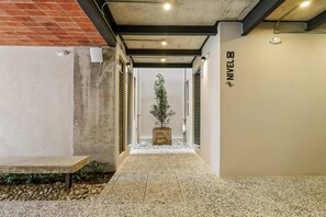 Um corredor com um banco de concreto, uma planta em vaso e uma placa indicando 'NIVEAU 8'.